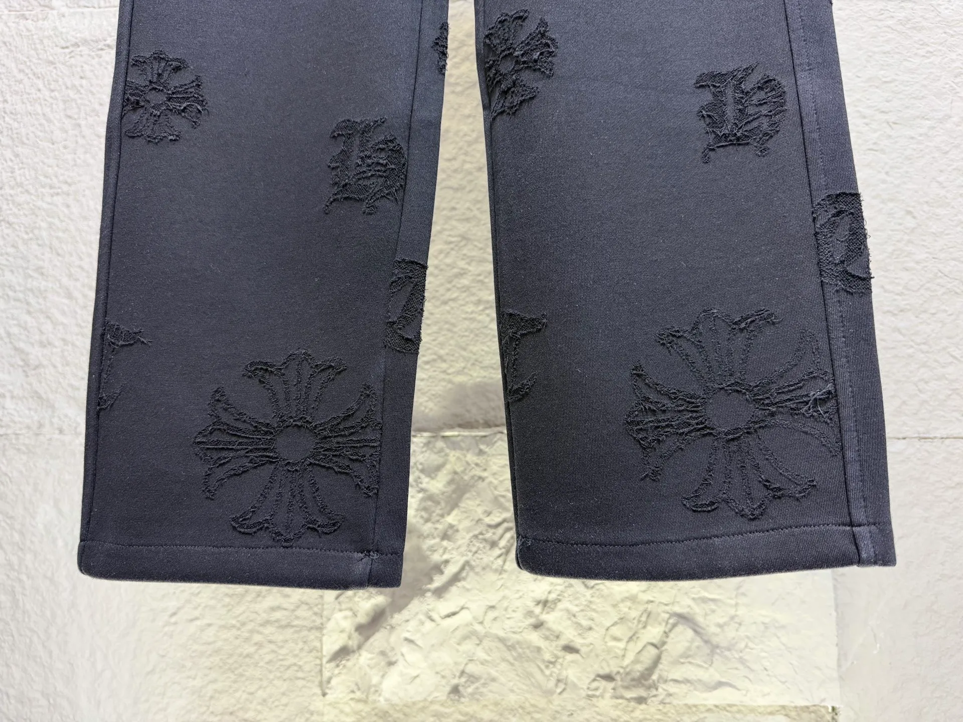 CH/Cro Heart 2026ss Burnt Flower Straight-leg Sweatpants Classic heavy-weight sweatpants with gray tones, Retro street style full-fitting, direct recognition, same style for men and women. ●Three-dimensional patchwork technology: The whole body is covered with Gothic letters + cross flower totems, using raw edge patchwork embroidery, with a mustache-like old texture, and uneven and layered patterns. It is not an ordinary print, and it is durable and not easy to fall off. ●Style tailoring: Loose, straight and wide-legged version, modifying the shape of the legs, hiding the flesh neatly, not flattering the figure, with an online drape, and the upper body has a relaxed street tone. ●Fabric and waist: Heavy knitted terry fabric, thick and soft, with good drape; elastic drawstring waist, with branded metal engraved rope ends, easy to put on and take off, and strong waist adaptability. ●Detailed design: The side pockets are convenient for carrying items, and the back pocket is decorated with cross-pattern patches. The front and rear patterns echo each other. Every detail is highly recognizable to the brand. ●Wearing scenarios: Suitable for street wear, daily outings, and trendy wear. Paired with sweaters, denim jackets, and leather jackets, you can easily create an American retro cool style. ●The overall gray base is paired with Cream White patches, which are low-key yet impactful. They are both comfortable and trendy. Versatile sweatpants, a must-have for fashionistas, are also available at the counter. SIZE：M L XL XXL XXXL